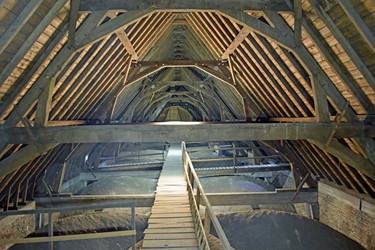 <p>Overzicht van de kapconstructie van de Grote Kerk in Elst, met gestapelde eiken spanten die rusten op trekbalken met korbeelstellen van beton. </p>
